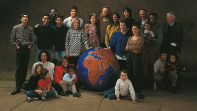 Scène avec de nombreuses personnes de tout âge et origine, debout ou assis autour d'un globe terrestre bleu et orange