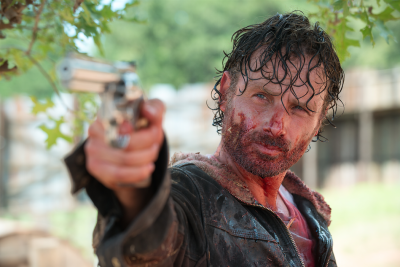 Rick holding a gun covered in sweat and blood